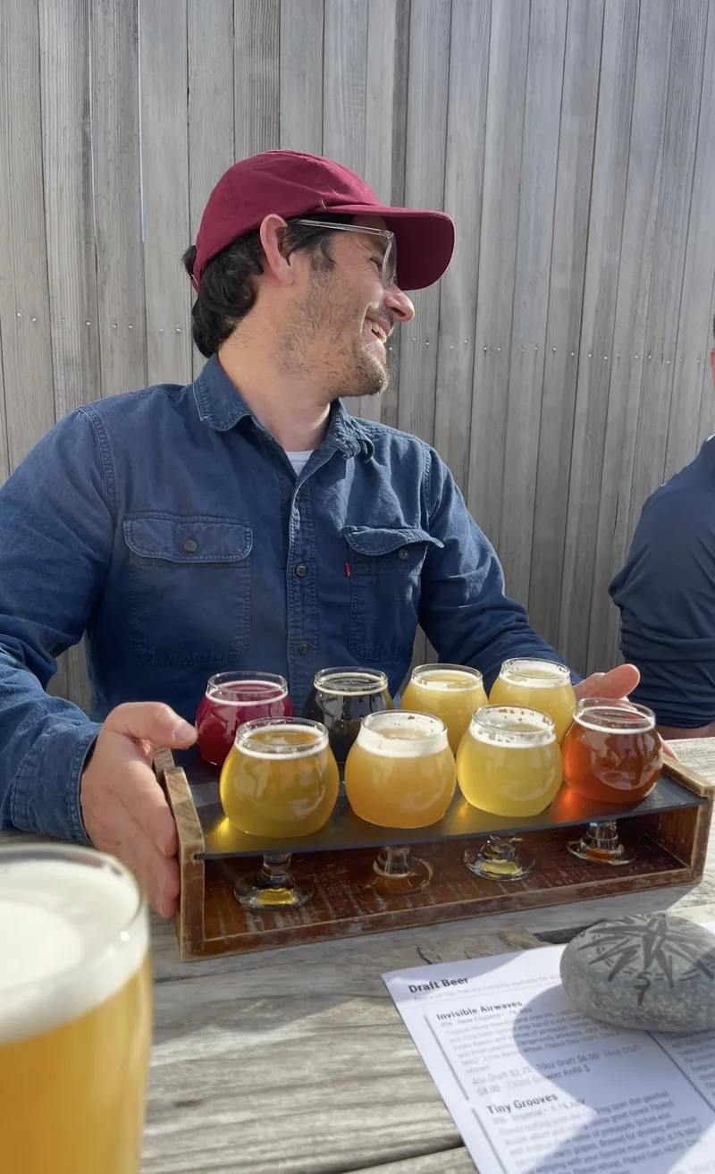 A beer flight of eight pours on the patio at Stellwagen Beer Company in Marshfield, MA, with the draft list on the table